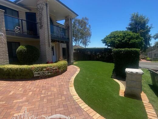 Synthetic turf laid around pavers and stepping stones