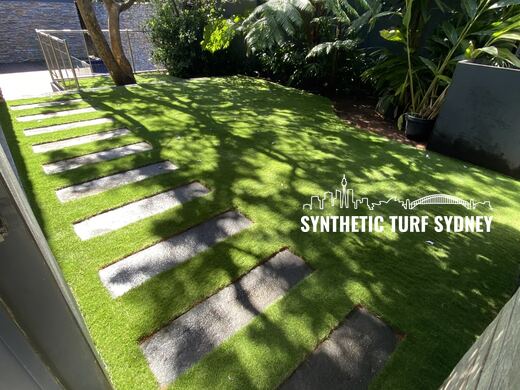 Synthetic turf laid around pavers and stepping stones