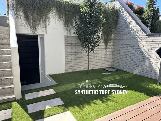 Synthetic turf laid around pavers and stepping stones