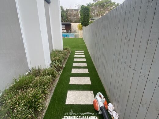 Synthetic turf laid around pavers and stepping stones