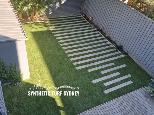 Synthetic turf laid around pavers and stepping stones