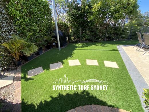 Synthetic turf laid around pavers and stepping stones