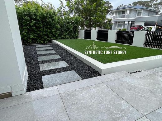 Synthetic turf laid around pavers and stepping stones