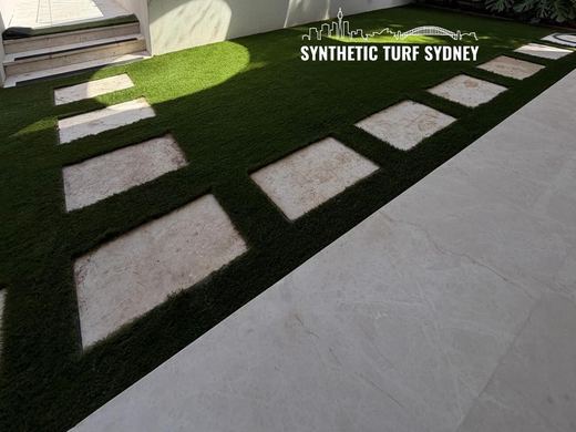 Synthetic turf laid around pavers and stepping stones